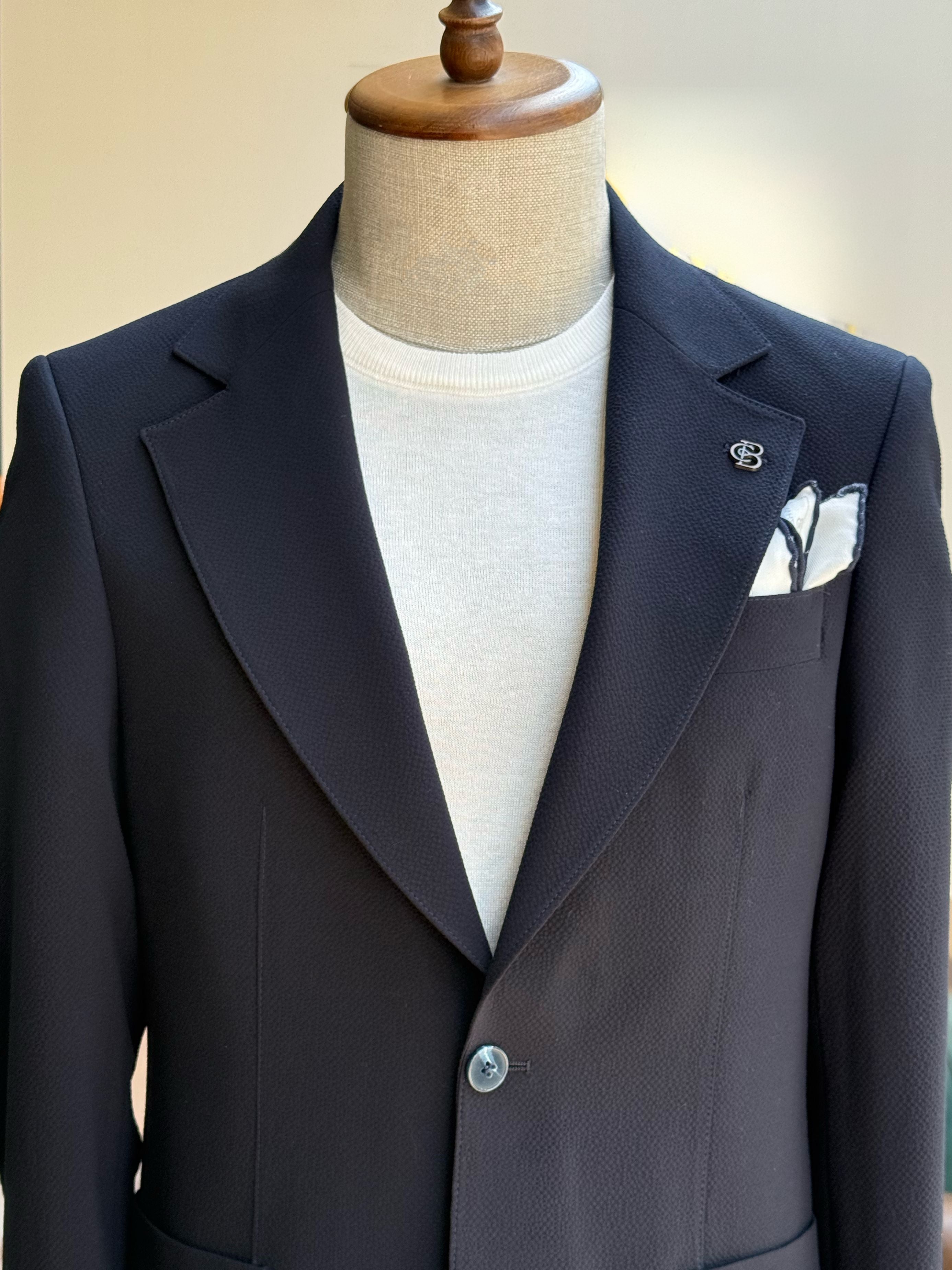 Navy single-breasted blazer displaying back panel and center vent detail, rear view
